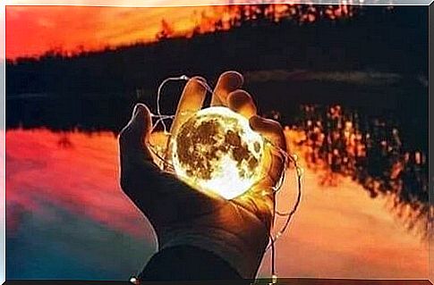 A person on a lake with the moon in hand