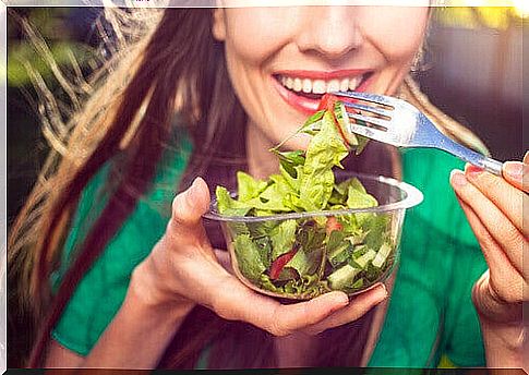 Smiling woman holding salad bowl