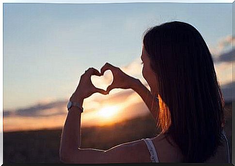 Woman makes a heart sign and learns to love herself