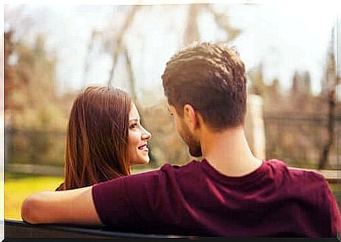 A happy couple sitting on a bench.