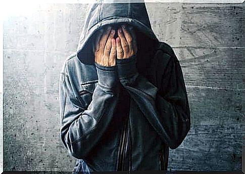 Man with hood covers face with hands