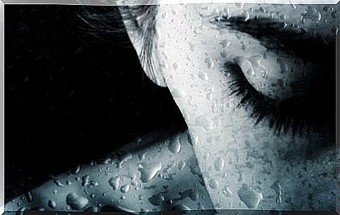 Woman crying behind wet glass