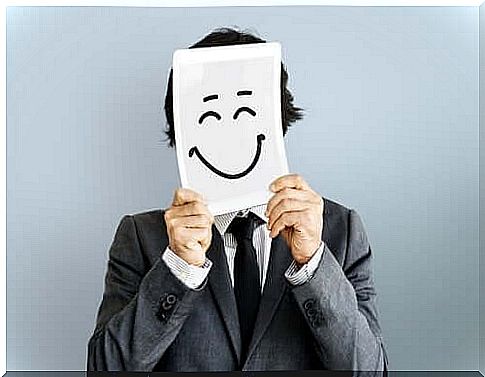 A man holding a happy face drawn on a piece of paper.