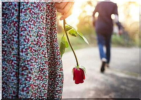 A man walking away from a woman holding a rose